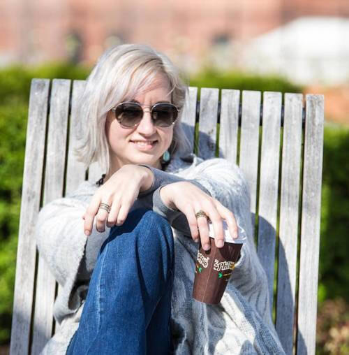 Alumna Tiffany Aurora sitting in a chair outside with sunglasses on.